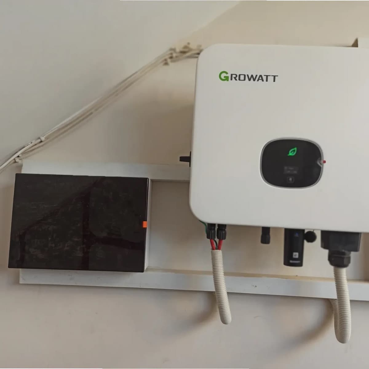 Growatt on-grid inverter mounted on a wall next to its DC isolator